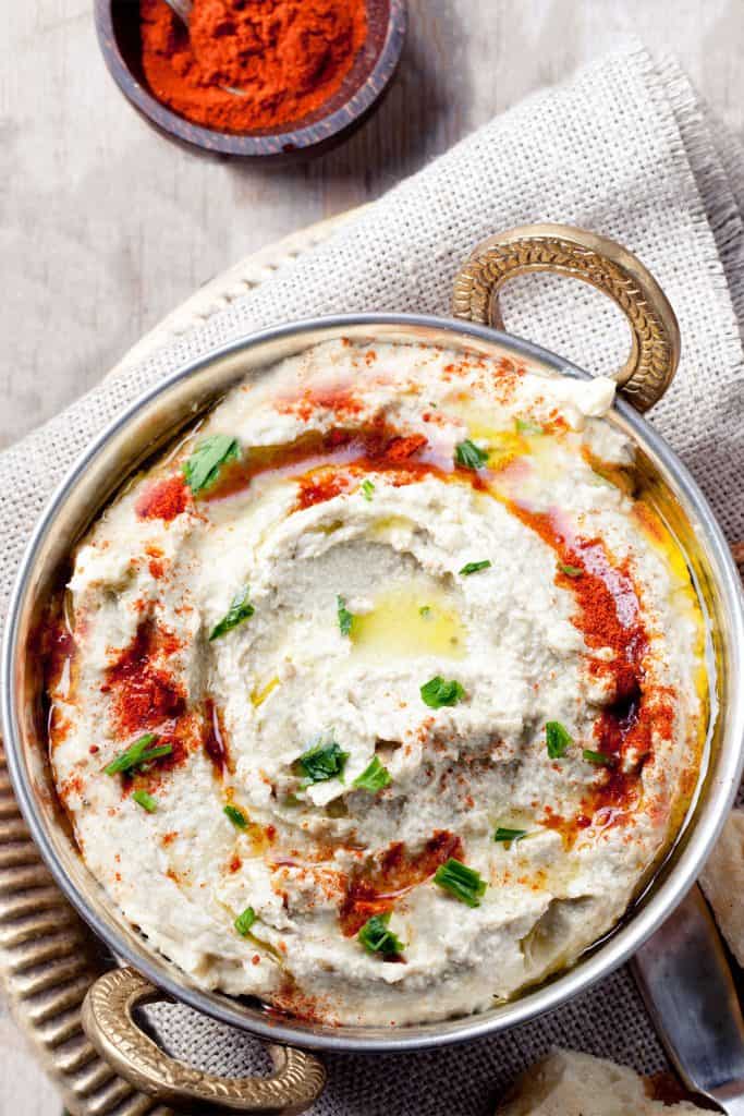 a plate of Baba Ghanouj garlished with olive oil, paprika and chopped parsley