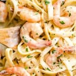 a pan of Fettuccine Alfredo with shrimp and garnished with parsley