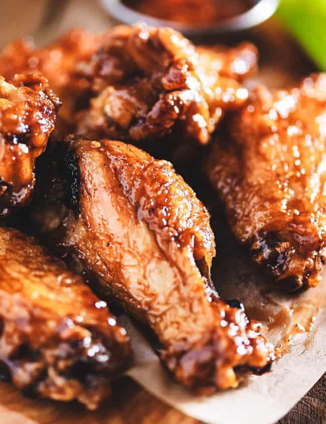 Chicken wings on a wood block with dipping sauce in the background