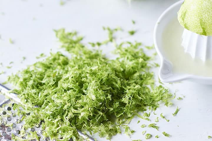 lime zest on a table with juice in the background