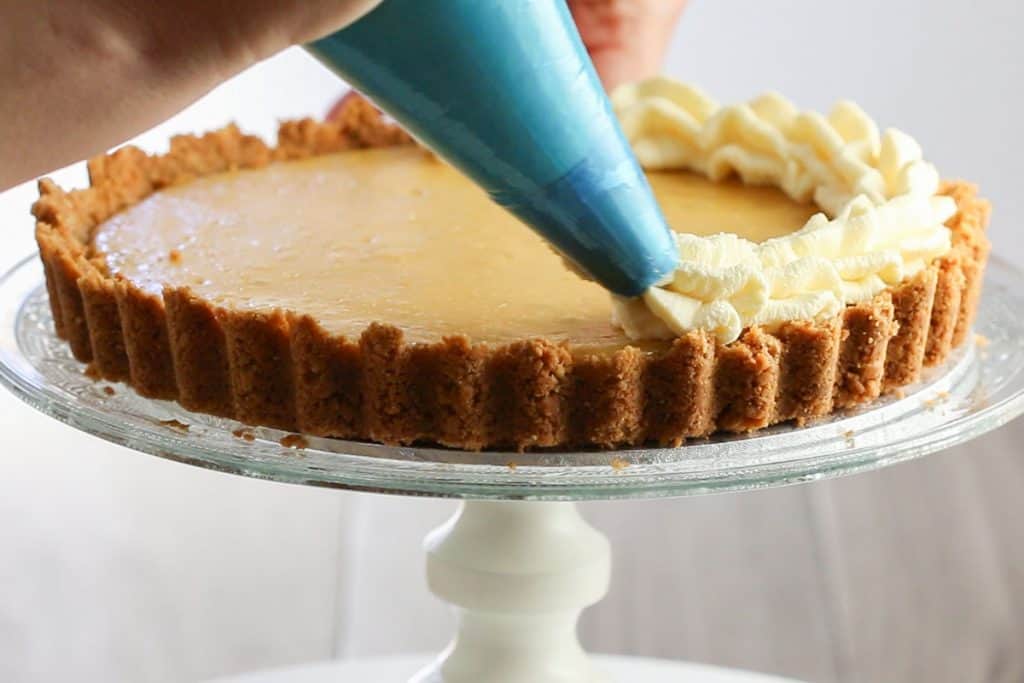 whipped cream being piped on to the pie