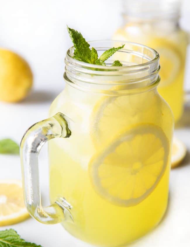 a glass of lemonade with lemon slices and fresh mint as garnish