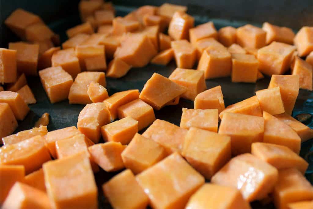 a cutting board with cubes of sweet potatoes