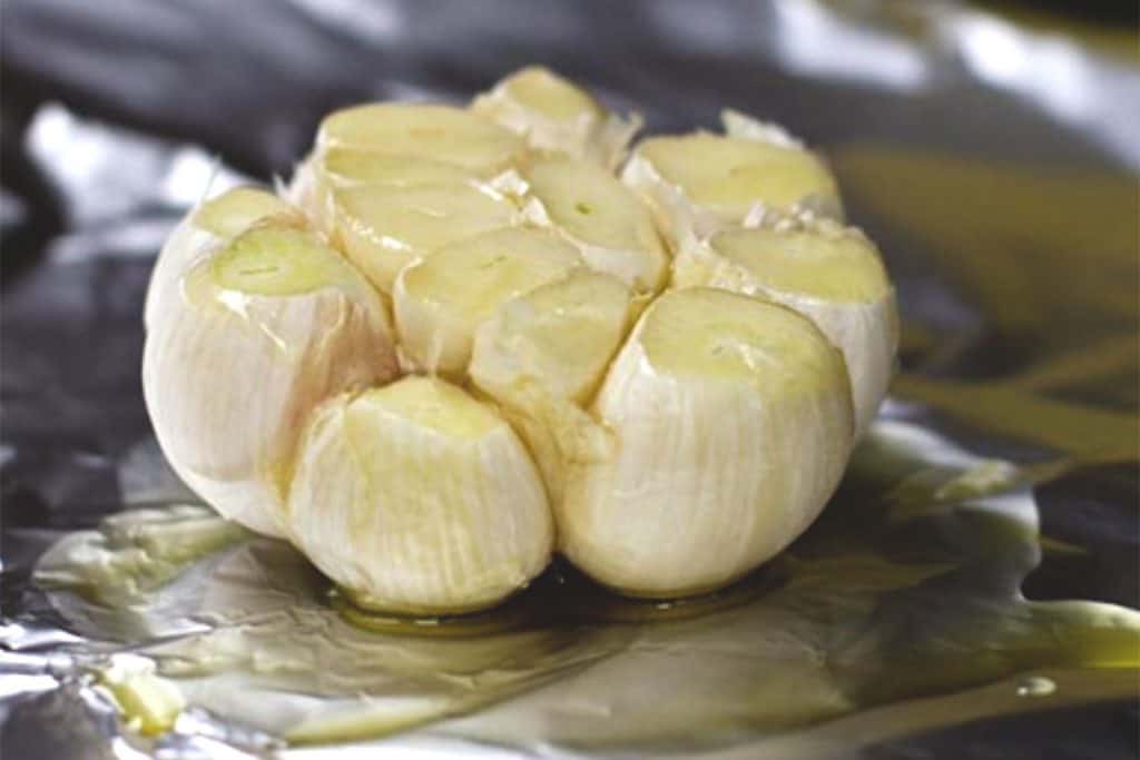 a head of garlic with the top trimmed off drizzed with olive oil