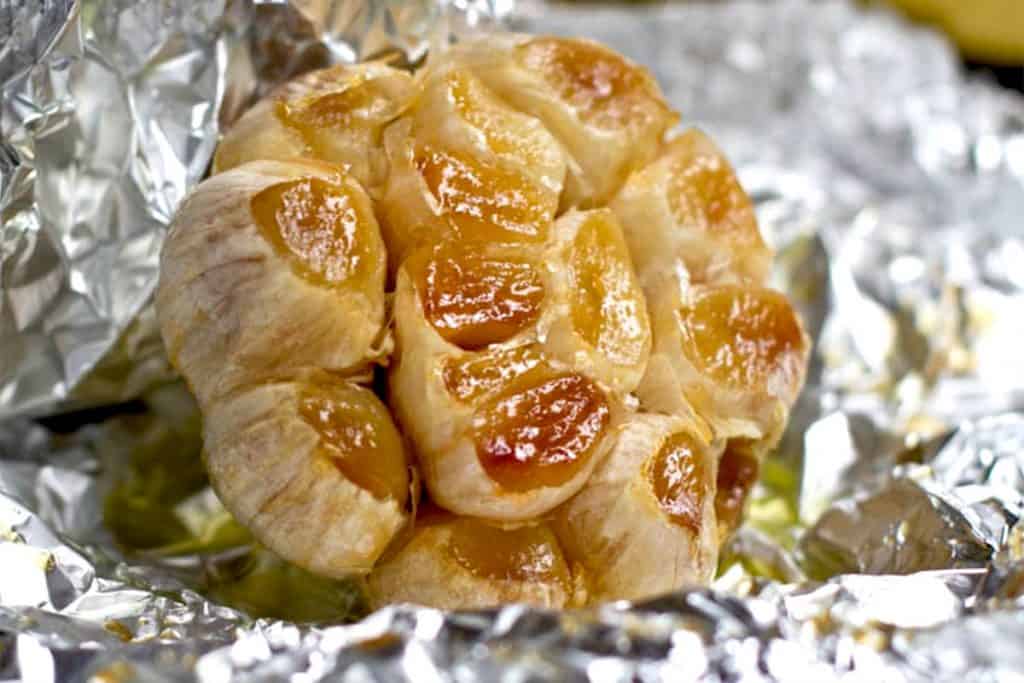 golden roasted garlic sitting on foil
