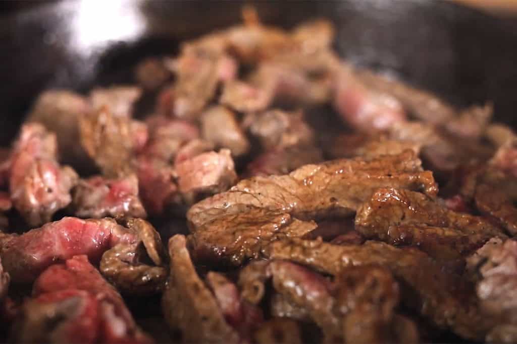 The browned beef srips in the pan