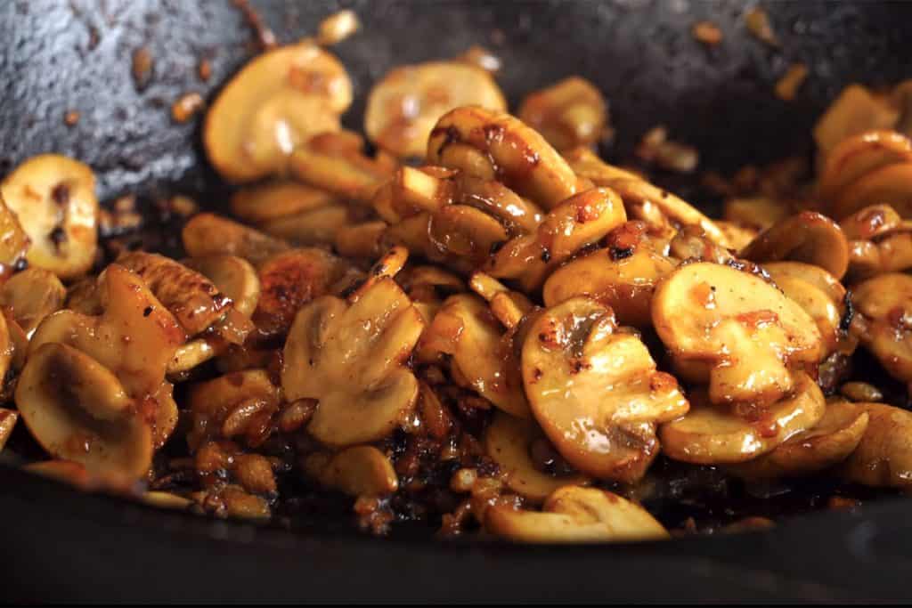 mushrooms cooking in a pan with onion