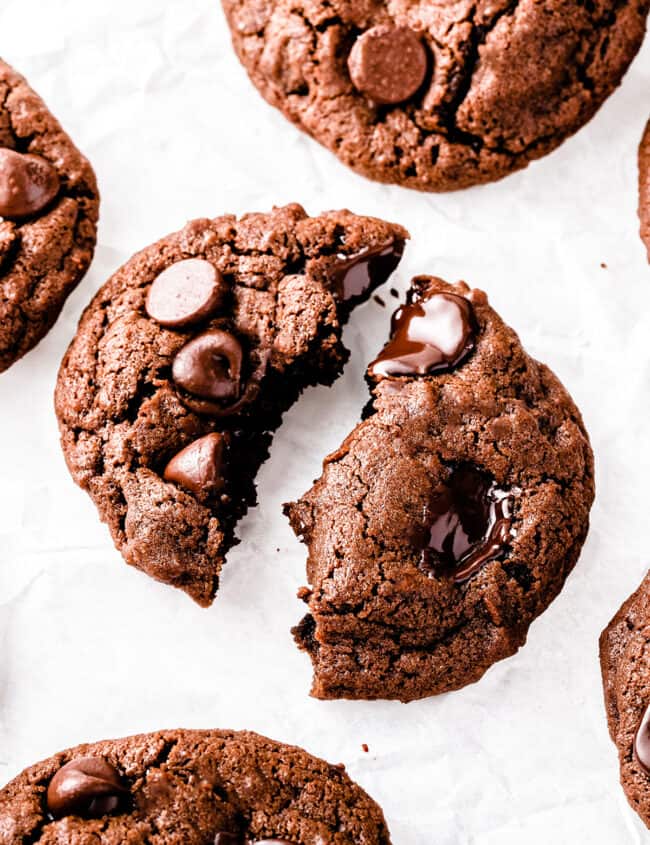 Double Chocolate Chip Cookies on a white background with one broken open to show gooey chocolate chips
