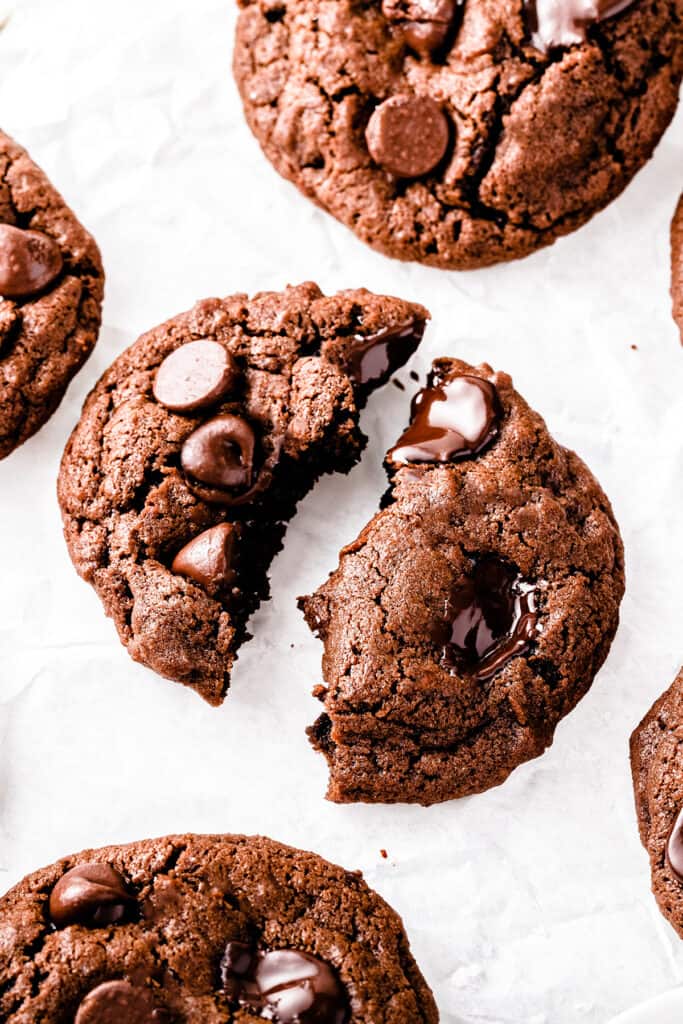 Double Chocolate Chip Cookies on a white background with one broken open to show gooey chocolate chips