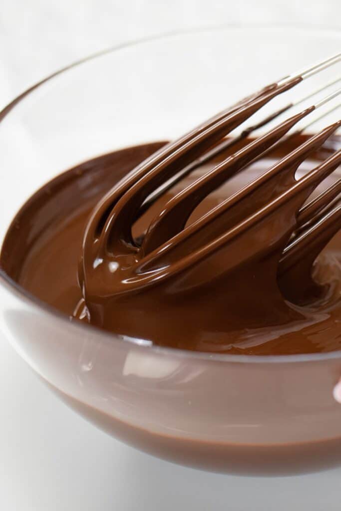 Melted chocolate being stirred by a whisk in a bowl