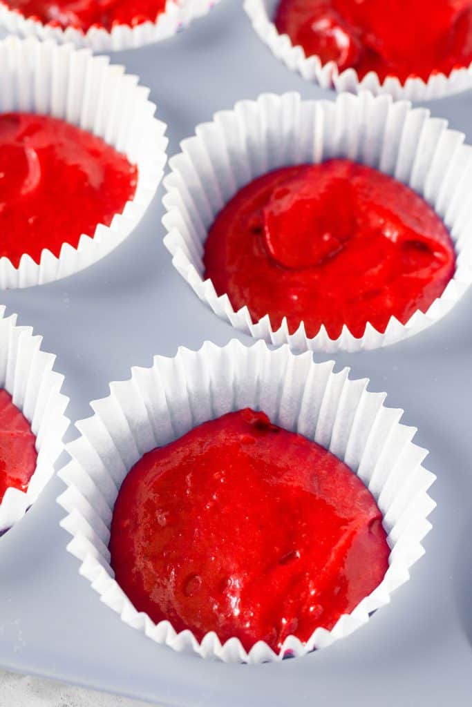 red cake batter added to cupcake papers in a pan