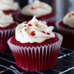 Red Cupcakes swirled with frosting and sprinkled with cake crumbs and more cupcakes in the background.