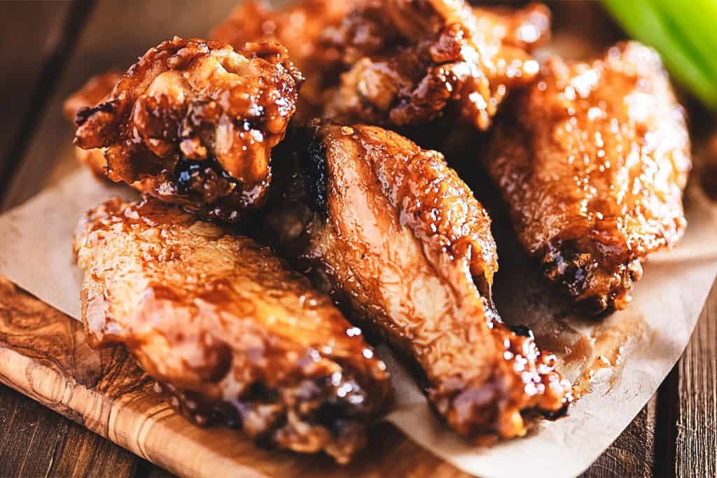 Chicken wings on a wood block with dipping sauce in the background
