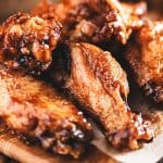 Chicken wings on a wood block with dipping sauce in the background
