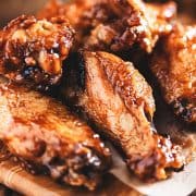 Chicken wings on a wood block with dipping sauce in the background