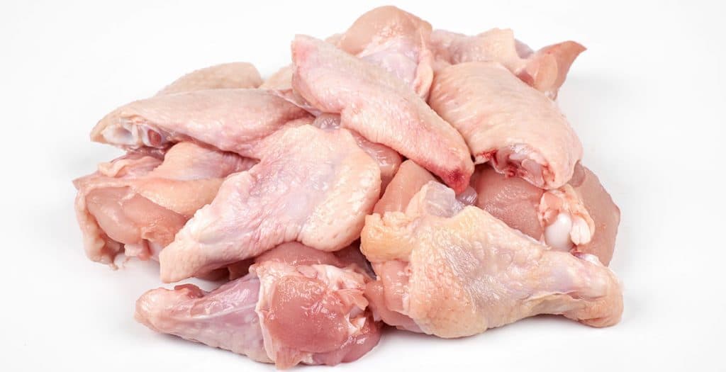 a pile of raw chicken wings with a white background