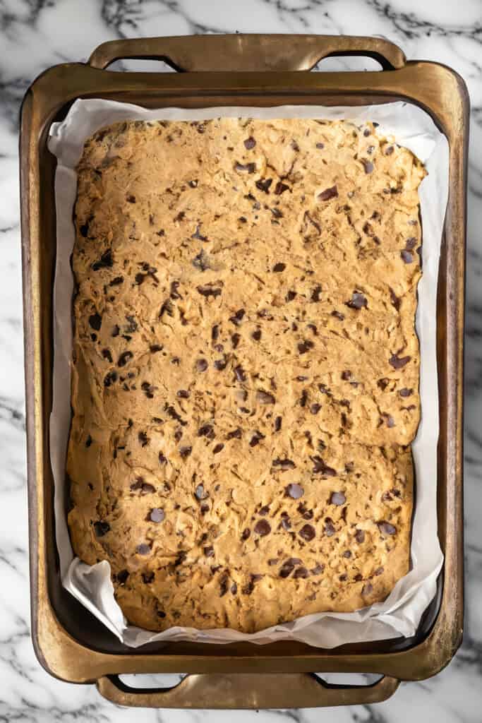 The chocolate chip blondie dough spread into a pan ready to bake.