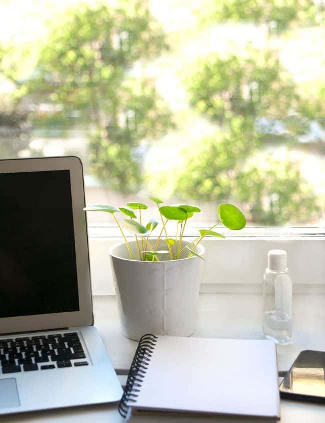 a laptop and notebook in front of a window
