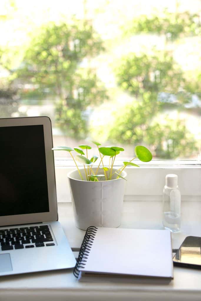 a laptop and notebook in front of a window