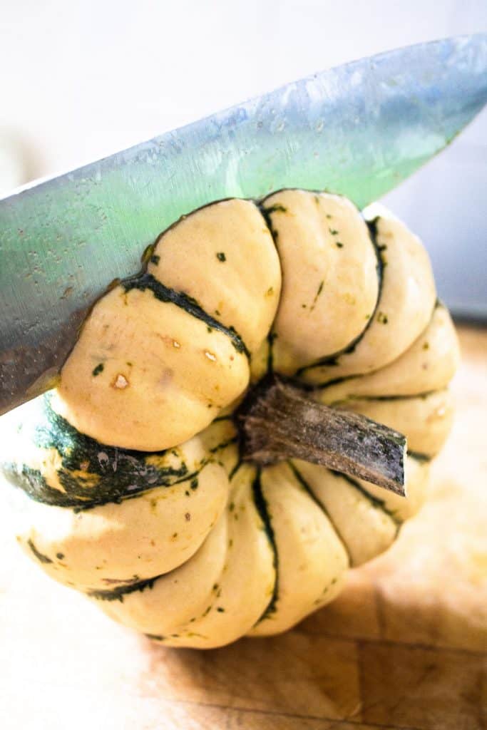 A sharp knife slicing the top off a squash