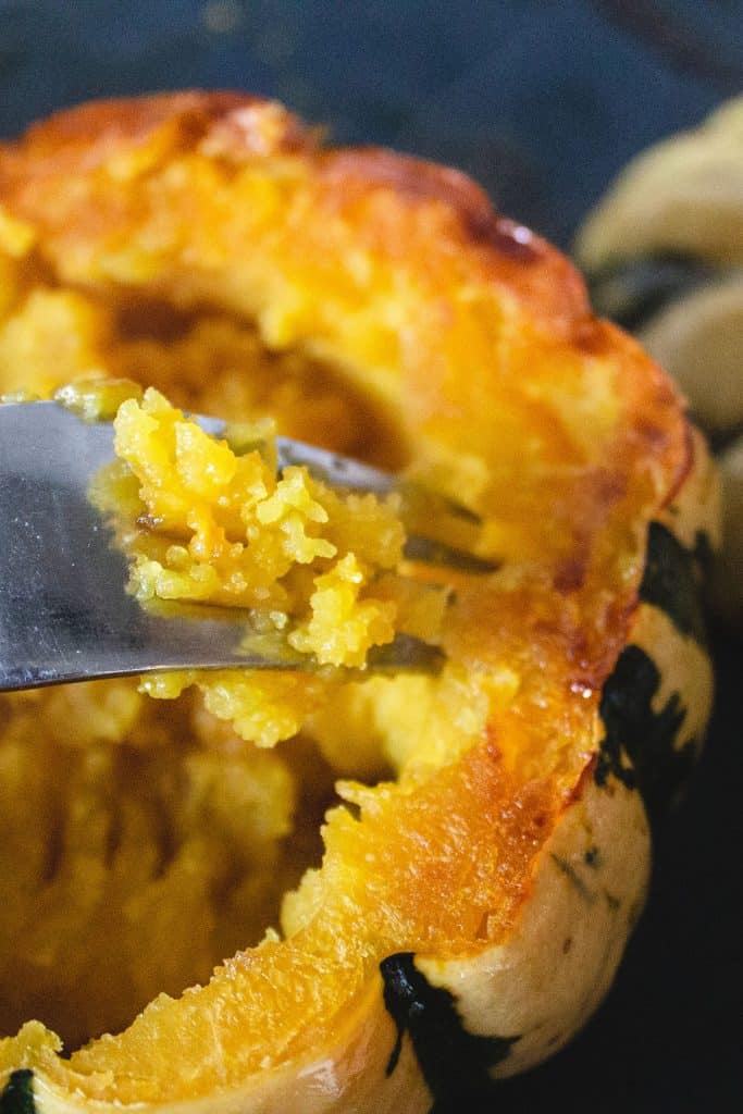 a fork mashing the inside of roasted squash