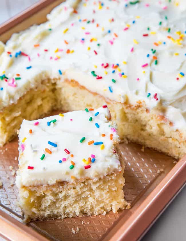 a sheet pan of vanilla cake with a slice cut out of it