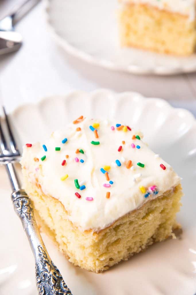 vanilla cake on a plate topped with frosting and sprinkles