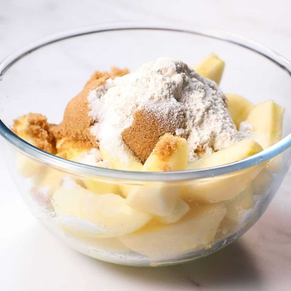 Four and sugar in a bowl with sliced apples