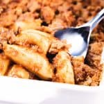 A spoon scooping out a serving of apples with crumb topping