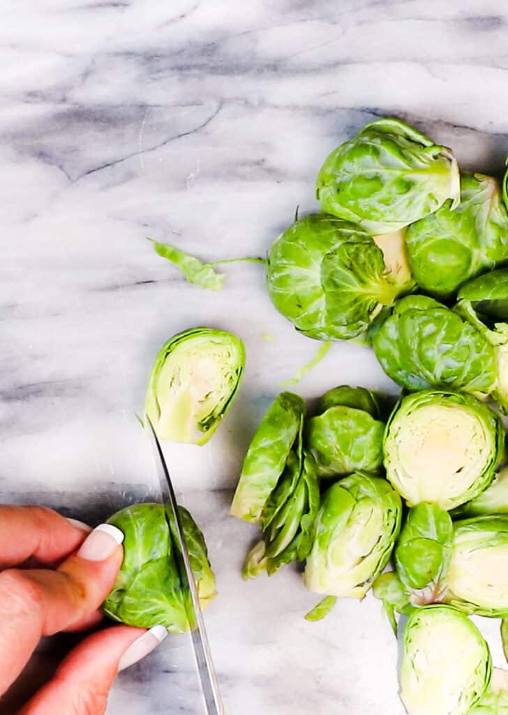 brussels sprouts being sliced on a cutting board