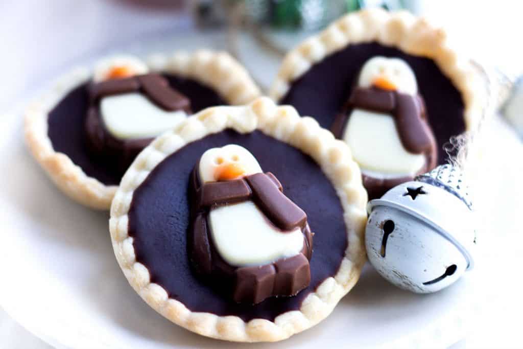 Three chcolate tarts on a plate with christmas decorations