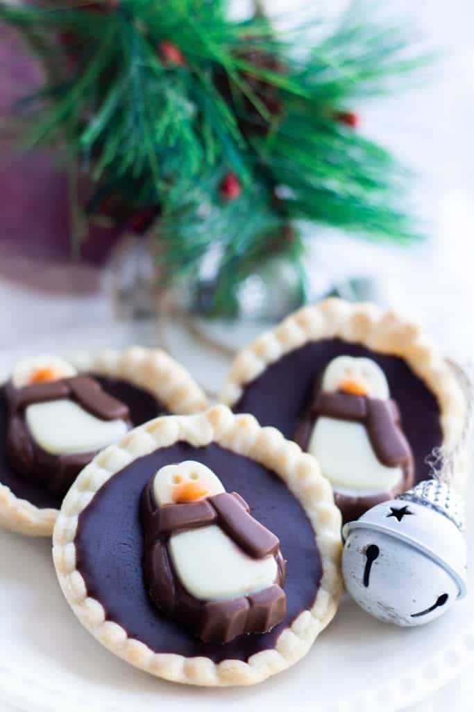 Three chcolate tarts on a plate with christmas decorations