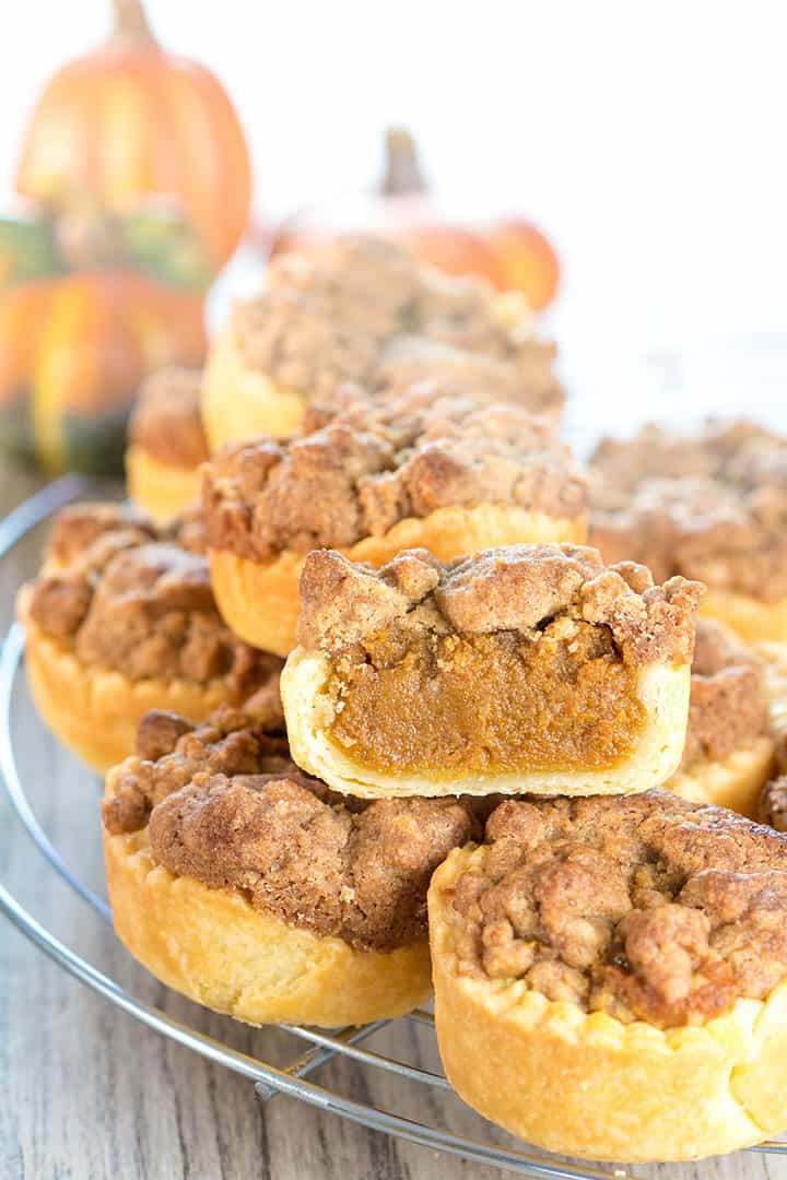 Pumpkin Tarts stacked on a cooling rack with one cut open to show the filling