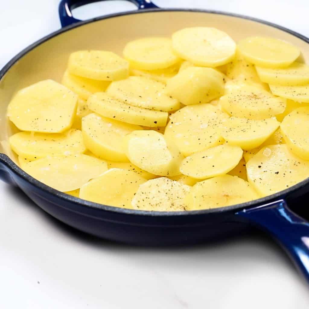 sliced potatoes added to a pan