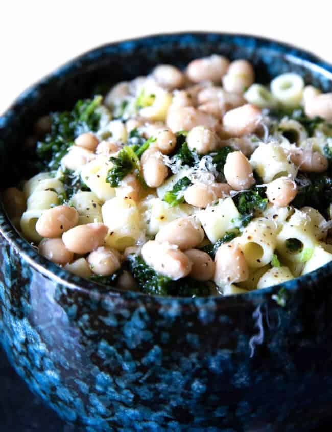 a bowl of white bean soup piled high with pasta and spinach