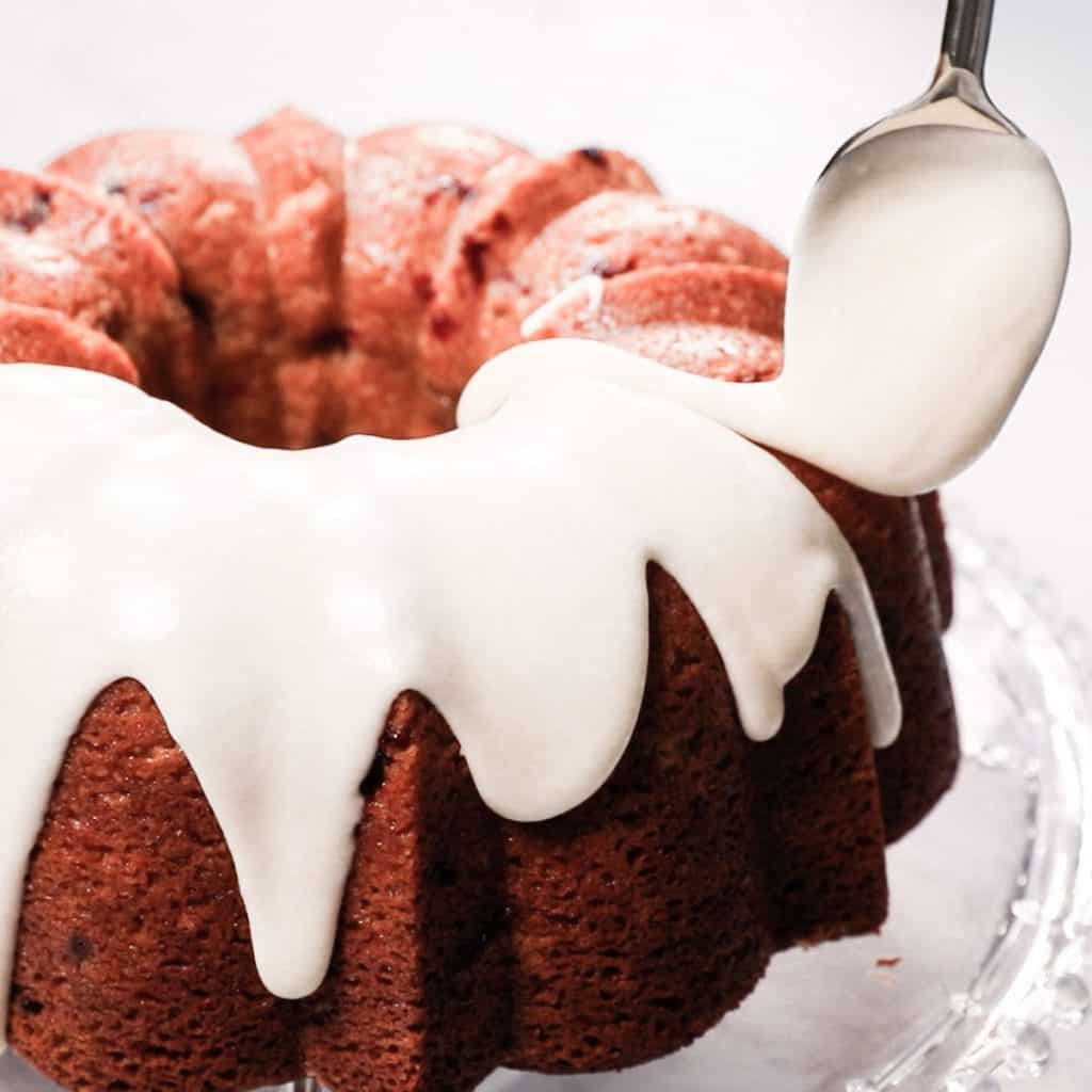 the glaze being spooned onto the cake