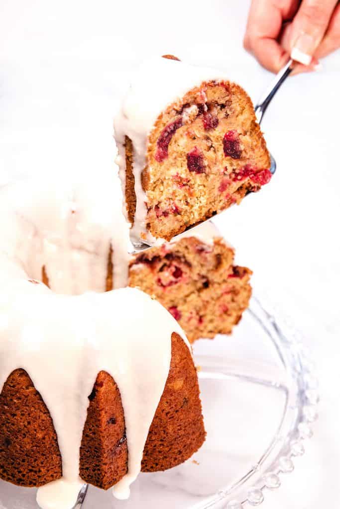 a slice of cake being cut out of the cranberry christmas cake