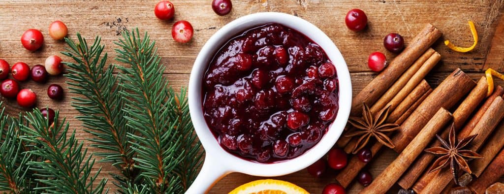 Cranberry sauce in ceramic saucepan with ingredients for cooking