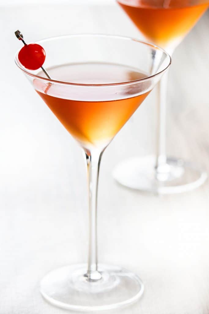 A Manhattan in a cocktail glass with a cherry in it