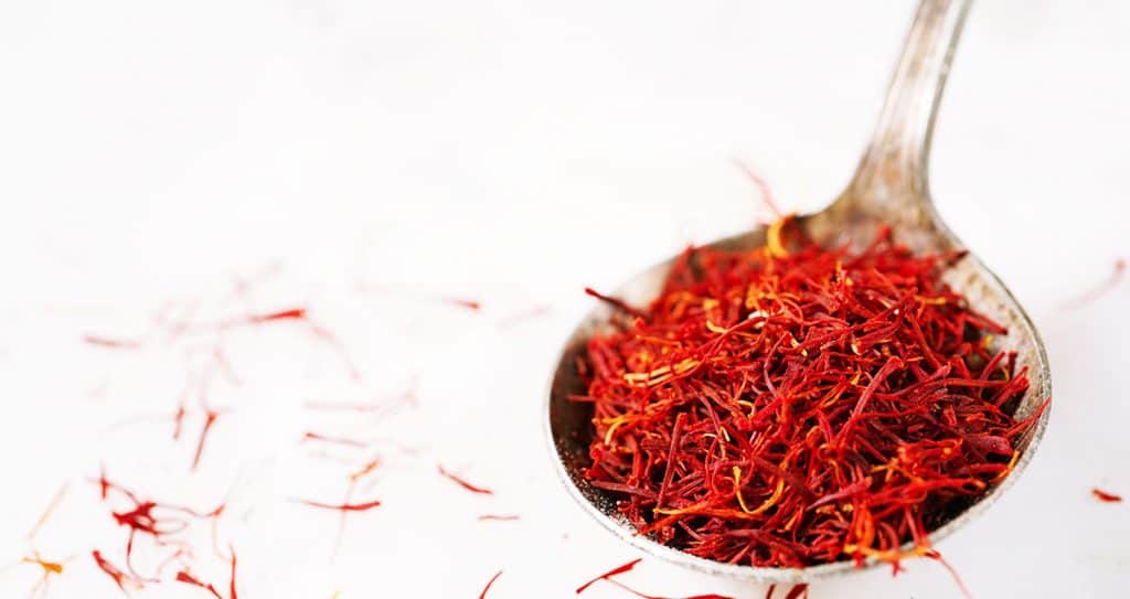 Saffron threads in a rustic spoon isolated on white