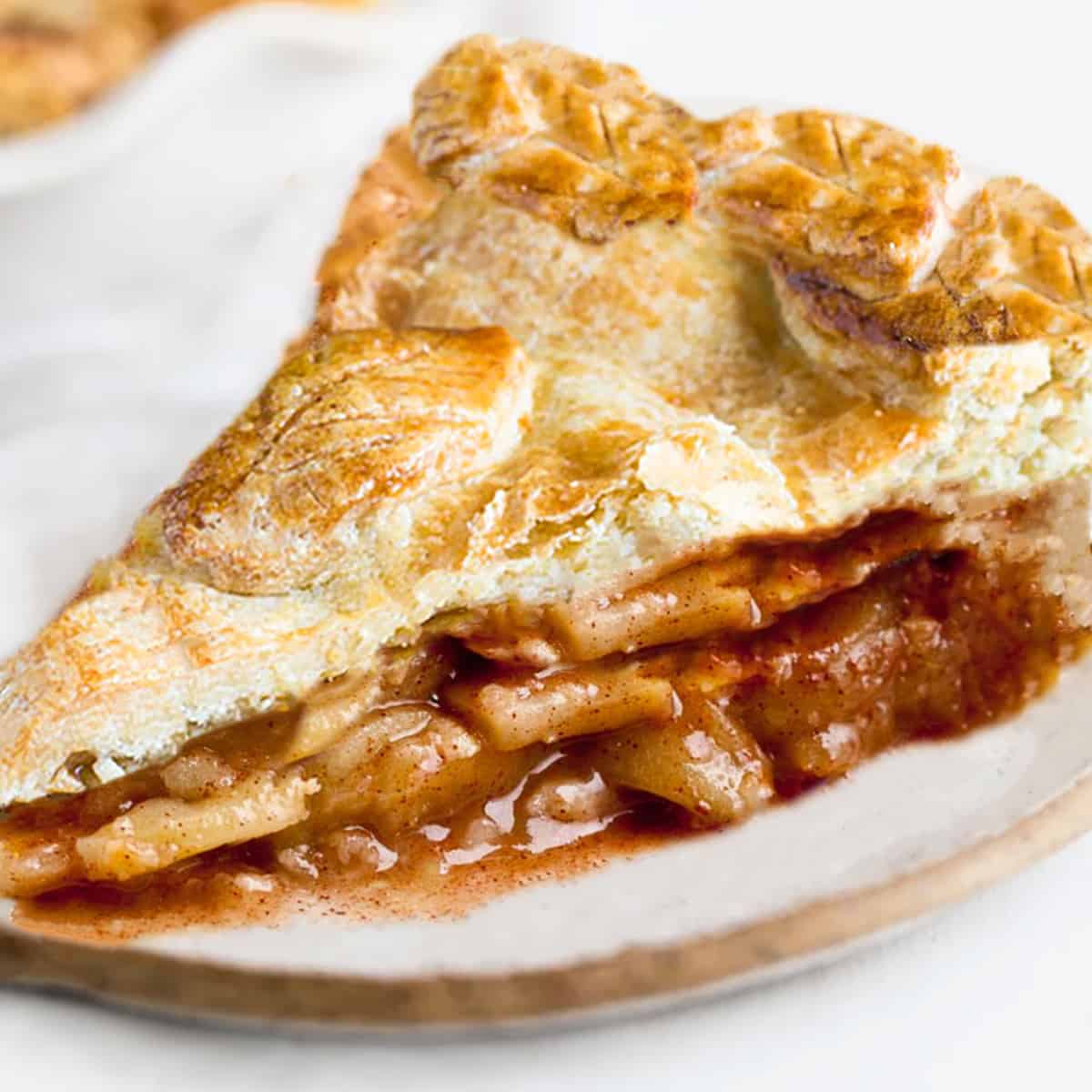 A slice of apple pie with a golen applie pie filling