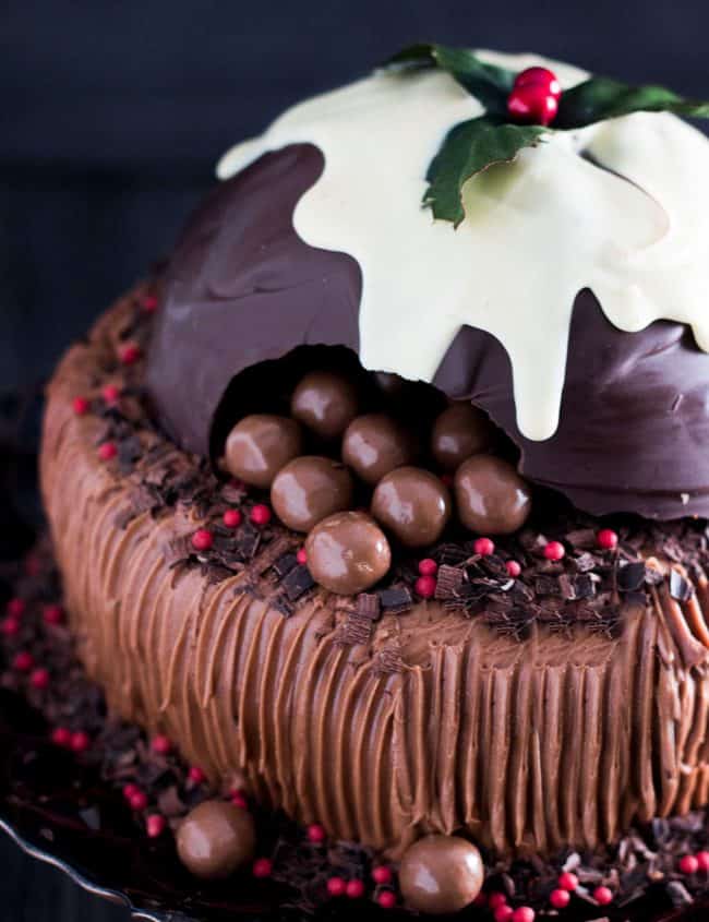 a chocolate cake topped with a christmas pudding made out of chocolate broken open to reveal candy inside