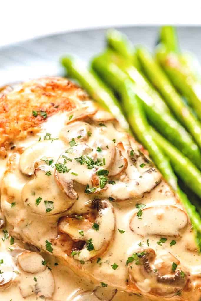 creamy mushroom chicken served on a plate with asparagus.