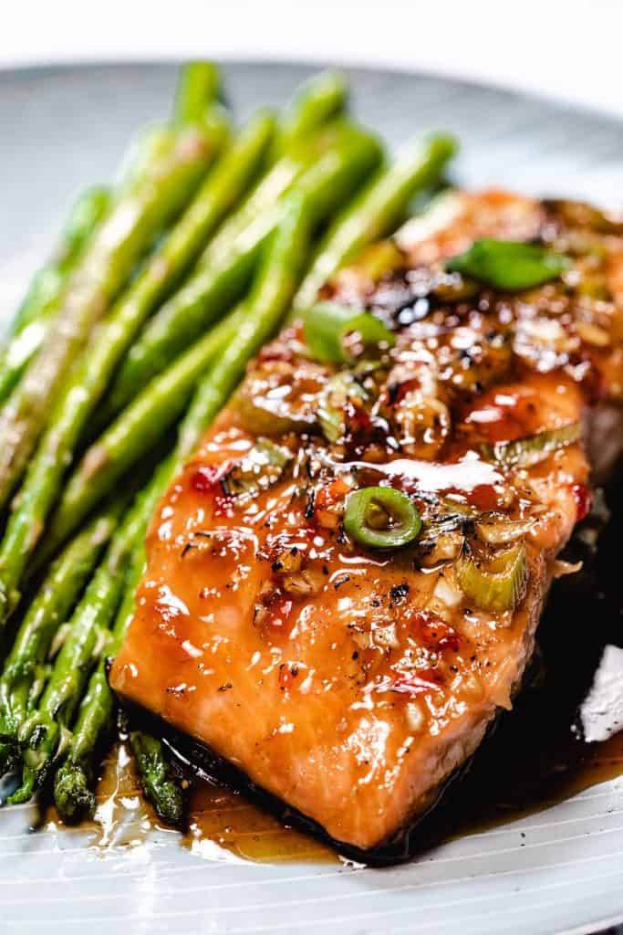 glazed salmon on a plate with asparagus next to it.