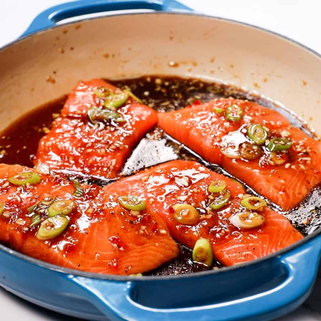 salmon in a pan with soy sauce, honey and green onions