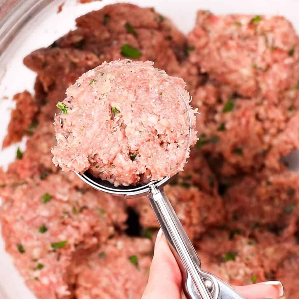 meatball mixture being formed into a ball with a scoop