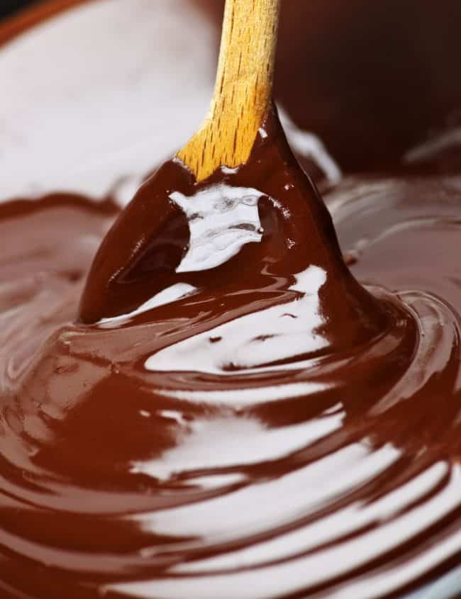 Wooden spoon stirring soft melted rich chocolate