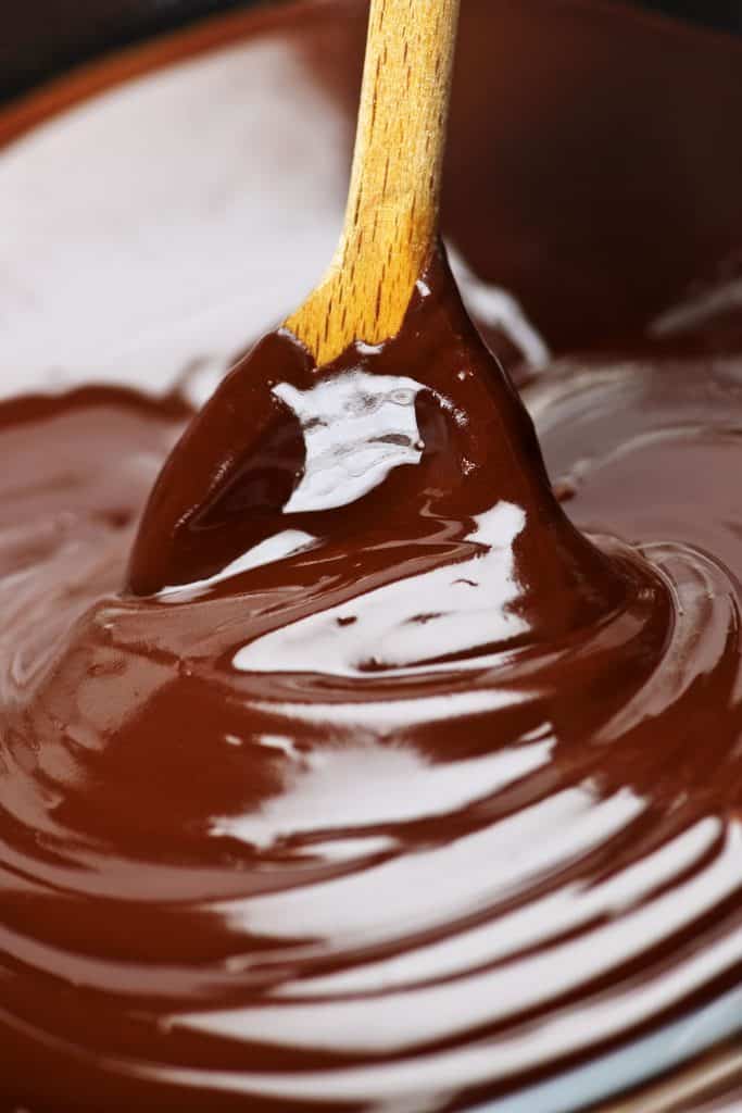 Wooden spoon stirring soft melted rich chocolate