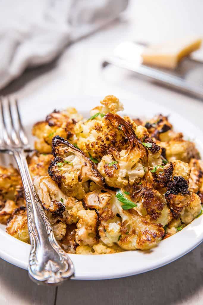 roasted cauliflower in a bowl ready to serve with a fork beside it.