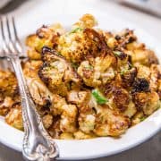 roasted cauliflower in a bowl ready to serve with a fork beside it.